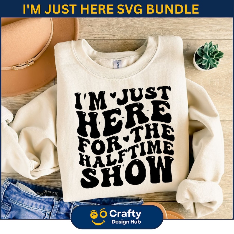 May include: A white sweatshirt with the text "I'm Just Here For The Halftime Show" in black retro-style lettering. The text is arranged in a circular pattern with a heart symbol between the words "I'm" and "Just" and between the words "For" and "The".