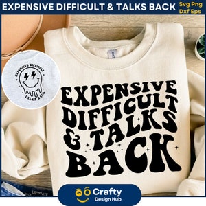 Puede incluir: Una sudadera beige con texto negro que dice "EXPENSIVE DIFFICULT & TALKS BACK" en una fuente retro. El texto está rodeado de pequeñas estrellas.