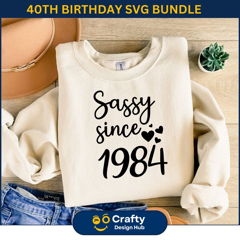 May include: A white sweatshirt with the text "Sassy since 1984" in black lettering. The text is in a cursive font and includes small hearts around the year.