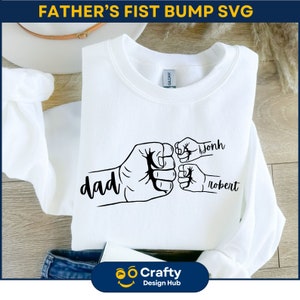 May include: White sweatshirt with a black graphic of three fists bumping. The largest fist says "dad" and the smaller fists say "john" and "robert".