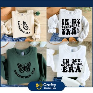 Op de afbeelding: Vier sweatshirts in cr&egrave;me, grijs, groen en wit. Elk heeft een grafisch ontwerp met de woorden "Godmother Era" of "In My Godmother Era" en een vlinderillustratie. De rechter benedenhoek heeft een logo met "Crafty Design Hub".