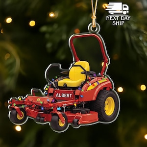 May include: Red lawn mower ornament with yellow seat and wheels, decorated with colorful lights. The name "ALBERT" is displayed on the front. A festive holiday decoration.