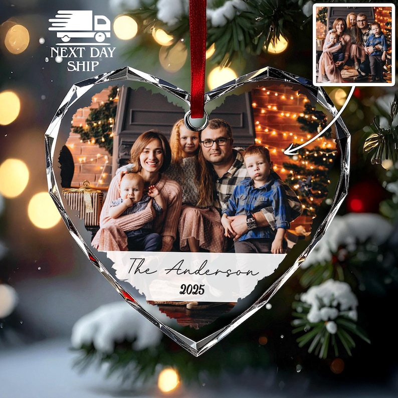 May include: A heart-shaped glass Christmas ornament featuring a printed family photograph of two adults and two children. The ornament has a red ribbon for hanging and includes the text The Anderson 2025 printed in black script and block font.