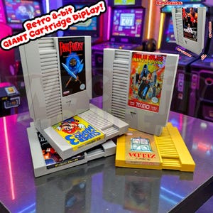 Peut inclure: Présentation de cartouches de jeux vidéo rétro 8 bits surdimensionnées. Les cartouches présentent des titres de jeux comme "Final Fantasy", "Ninja Gaiden" et "Super Mario 3". L'affichage comprend une cartouche jaune intitulée "Zelda". Le texte "Retro 8-bit GIANT Cartridge Display!" est visible.
