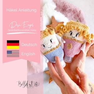 May include: Two crocheted angel hand sanitiser bottle covers. One is pink and the other is blue. Both have gold trim and a smiling face. The text "Desi-Engel" and "Desinfektionsmittel Hülle" is visible. The text "Häckel Anleitung" is also visible. The text "BellyArt" is visible at the bottom of the image.