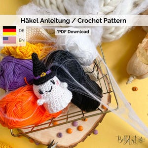 May include: A Halloween-themed crochet pattern. The image shows a small, white ghost wearing a black witch hat, set amongst skeins of orange, purple, white, and black yarn. The text "Häkel Anleitung / Crochet Pattern" is displayed.
