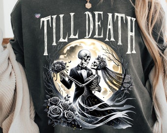 May include: A dark gray t-shirt with a graphic of a skeleton couple dancing under a full moon. The text "TILL DEATH" is printed above the graphic.