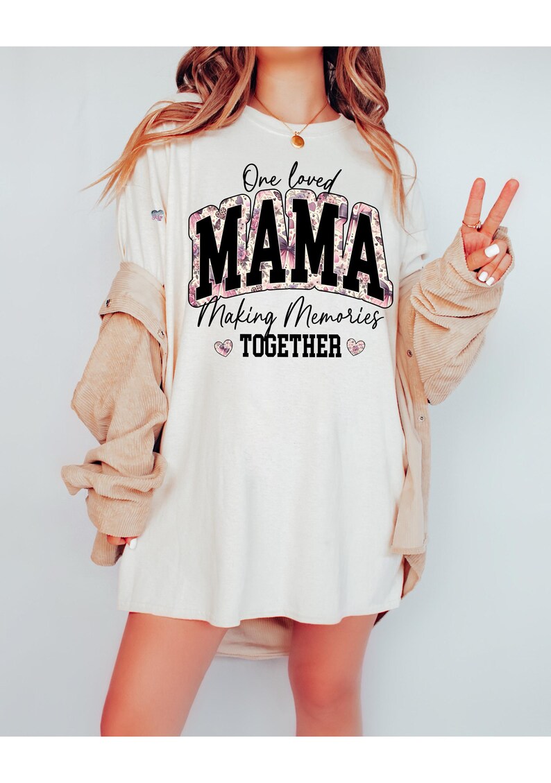 May include: White t-shirt with a floral design and the text "One loved MAMA Making Memories TOGETHER" in black.