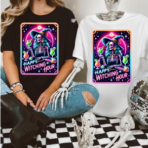 Pu&ograve; includere: Due t-shirt con una strega scheletro che indossa un cappello da strega e tiene un cocktail. Il testo sulle magliette recita "Happy Witching Hour".