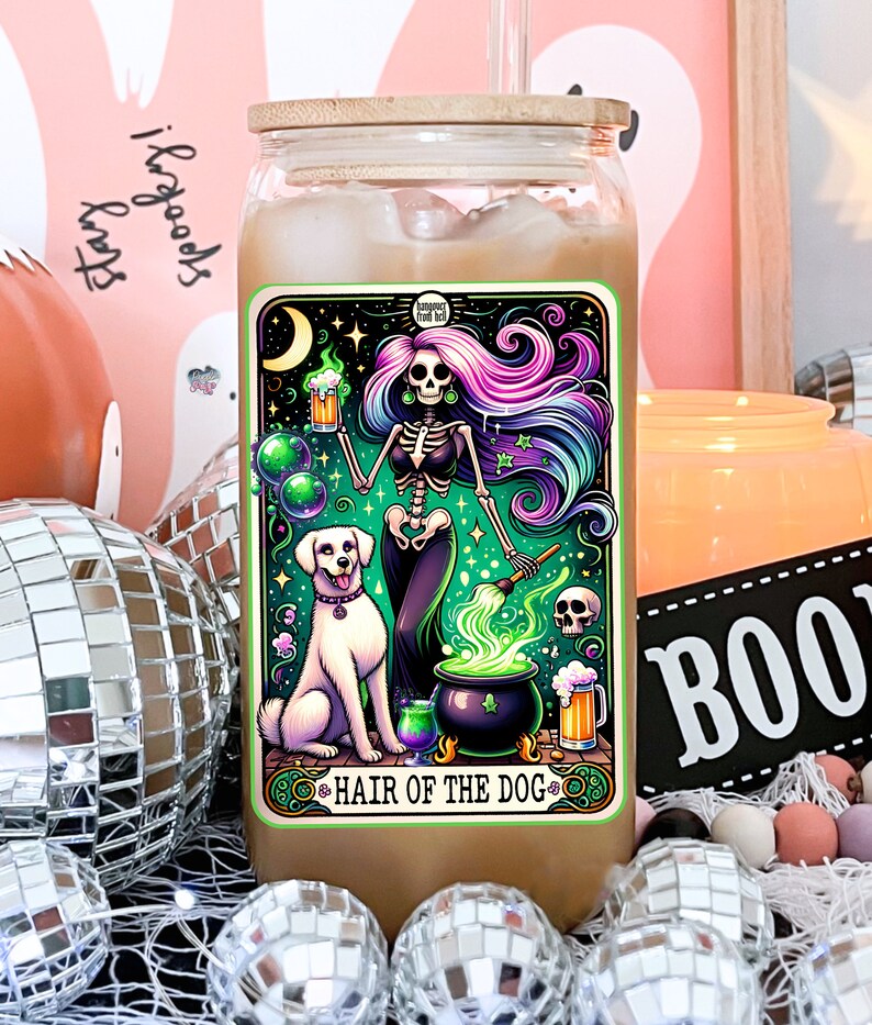 May include: A glass jar with a wooden lid and a colorful sticker featuring a skeleton with purple and blue hair holding a beer mug. The sticker says "Hair of the Dog" and has a green cauldron with a dog beside it.
