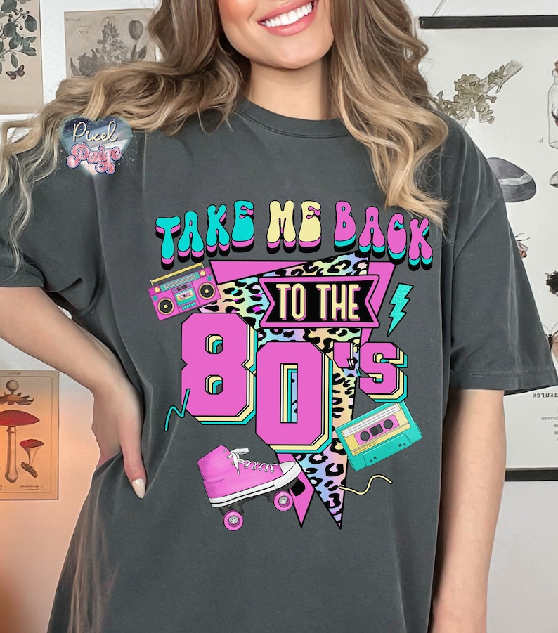 May include: A gray t-shirt with the text "Take Me Back To The 80's" in a colorful retro design. The design includes a boombox, roller skates, and a cassette tape.