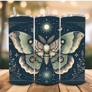 Puede incluir: Un juego de tres vasos de acero inoxidable con fondo azul oscuro y una ilustración detallada de una polilla con intrincados patrones, una luna y estrellas. Los vasos son perfectos para contener bebidas calientes o frías.