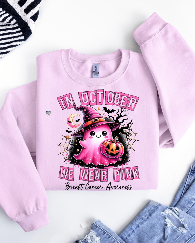 Peut inclure: Sweat-shirt rose avec un fant&ocirc;me portant un chapeau de sorci&egrave;re et tenant une citrouille. Le texte "In October We Wear Pink" et "Breast Cancer Awareness" est imprim&eacute; sur le sweat-shirt.