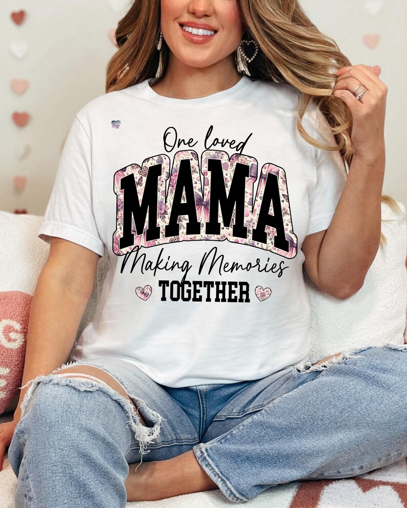 May include: White t-shirt with a floral design and the text "One loved MAMA Making Memories TOGETHER" in black.