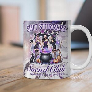 Op de afbeelding: Witte keramische mok met een paars, zwart en wit ontwerp met drie heksen met een ketel en de tekst "Shit Stirrers Social Club Witch please...tell me everything!"
