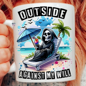 May include: White ceramic mug with a colorful illustration of a skeleton wearing a black robe and holding a tropical drink. The skeleton is sitting on a beach chair under an umbrella. The text "OUTSIDE AGAINST MY WILL" is printed on the mug.