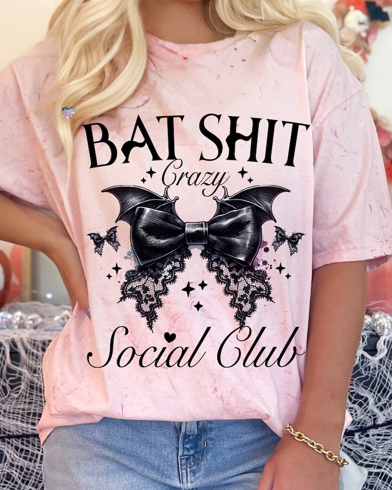 May include: Pink tie-dye t-shirt with a black bat and bow graphic. The text "Bat Shit Crazy Social Club" is printed on the shirt.