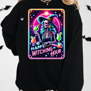 Pu&ograve; includere: Felpa nera con una grafica rosa, blu e verde neon di una strega scheletro che tiene un cocktail. La grafica dice "Happy Witching Hour".