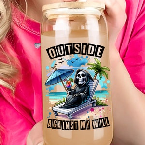 May include: A glass water bottle with a bamboo lid and a graphic of a skeleton on a beach chair with a cocktail. The text on the bottle reads "Outside Against My Will".