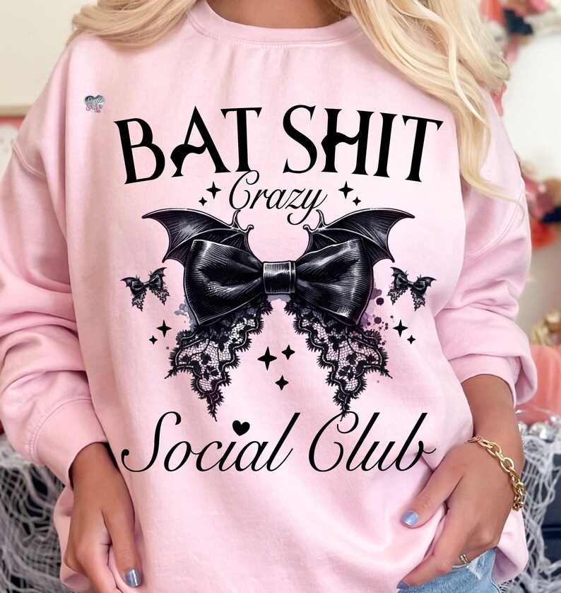 May include: Pink sweatshirt with a black bat and bow graphic. The text "Bat Shit Crazy Social Club" is printed on the front of the sweatshirt.