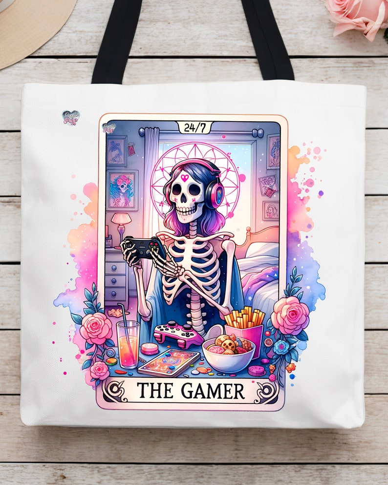 K&ouml;nnte beinhalten: Eine wei&szlig;e Einkaufstasche mit einer bunten Illustration eines Skeletts, das Videospiele spielt. Die Illustration ist im Stil einer Tarotkarte mit dem Text "The Gamer" und "24/7" auf der Karte.