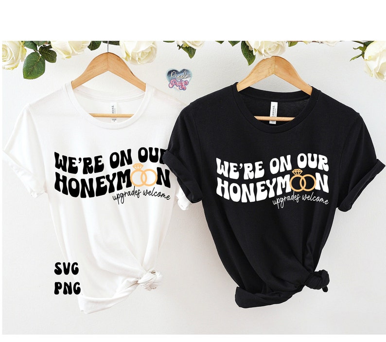 May include: Two t-shirts with the text "We're on our honeymoon" in a retro font. The text is in black and the shirts are white and black. The shirts are tied together with a knot.
