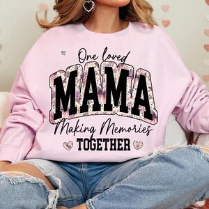 May include: Pink sweatshirt with a floral design and the text "One loved MAMA Making Memories TOGETHER" in black.