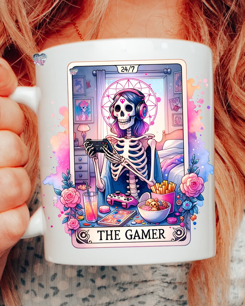 K&ouml;nnte beinhalten: Eine wei&szlig;e Keramiktasse mit einer bunten Illustration eines Skeletts, das Kopfh&ouml;rer tr&auml;gt und einen Videospielcontroller h&auml;lt. Der Text "24/7 THE GAMER" ist auf die Tasse gedruckt.