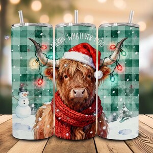 May include: A stainless steel tumbler with a festive design. The tumbler features a Highland cow wearing a Santa hat and a red scarf, adorned with Christmas lights. The words "Merry Whatever Moo" are printed on the tumbler. A snowman and a snowy forest scene are also depicted.