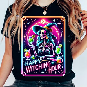 Pu&ograve; includere: Una maglietta nera con una grafica rosa neon, blu e verde di una strega scheletro che tiene un cocktail. La grafica &egrave; in una cornice in stile carta dei tarocchi con il testo "Happy Witching Hour".