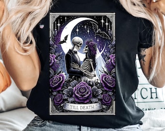 May include: Black t-shirt with a graphic of two skeletons dressed as a bride and groom. The skeletons are standing in front of a crescent moon and stars. The graphic is surrounded by purple roses and the text "Till Death".