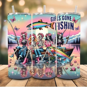 以下が含まれることがあります： 「GIRLS GONE FISHIN」の文字と、ボートから釣りをする骸骨たちの鮮やかなイラストが描かれたタンブラー。虹色のマス、蝶、花のアクセントが、美しい風景を背景にデザインされています。