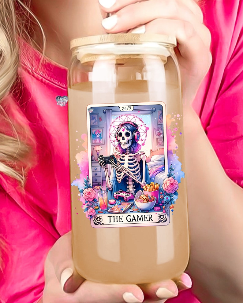 K&ouml;nnte beinhalten: Eine durchsichtige Glaswasserflasche mit einem Bambusdeckel und einem bunten Aufkleber, der ein Skelett zeigt, das Videospiele spielt. Der Aufkleber lautet "24/7 The Gamer".