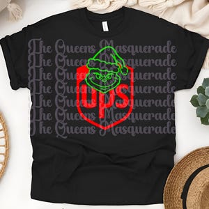 May include: Black t-shirt featuring a green Grinch face wearing a Santa hat, inside a red shield with the UPS logo. The shirt has the text "The Queens Masquerade" repeated across the shirt.