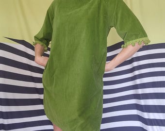 Puede incluir: Vestido de pana verde lima con mangas cortas y cuello redondo. El vestido tiene un corte holgado y presenta un ribete decorativo de pequeños pompones verdes en las mangas y el escote. El vestido tiene dos bolsillos.