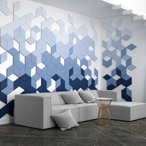 Könnte beinhalten: Ein modernes Wohnzimmer mit einem grauen Ecksofa und einer geometrischen Wandgestaltung mit blauen und weißen 3D-Fliesen. Ein kleiner goldfarbener Metalltisch steht vor dem Sofa.