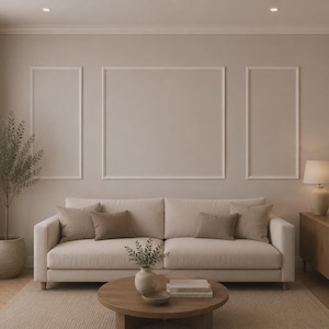 Könnte beinhalten: Ein neutralfarbener Wohnraum mit einem cremefarbenen Sofa und passenden Kissen. Ein runder Holztisch zeigt dekorative Gegenstände. Der Raum umfasst einen beigen Teppich, eine Topfpflanze und gerahmte Wandkunst.