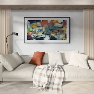May include: A rectangular framed wall art piece featuring an abstract architectural composition with geometric shapes in shades of orange, yellow, blue, and black, displayed above a white sofa with a rust-colored pillow and a plaid throw blanket.