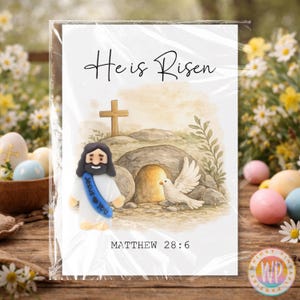 May include: A greeting card with the text "He is Risen" in script. The card features an illustration of Jesus, a cross, and a dove. The text "Matthew 28:6" is at the bottom. The card is in a clear plastic sleeve.