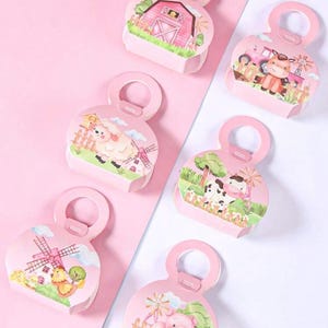 May include: Six pink gift boxes with handle-shaped tops, each featuring a different farm animal scene. The illustrations include a barn, cow, sheep, pig, and chicken, with windmills and green grass. The boxes are arranged on a pink and white background.