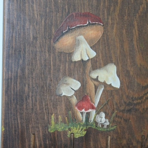 May include: Wooden spool holder with three spools of thread. The holder is painted with a whimsical mushroom design in shades of brown, red, and white.