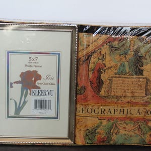 May include: A 5x7 photo frame with a silver-colored beaded border, packaged with a decorative box. The frame has a white mat and the text "Iris" and "KLEERVU". The box features a vintage map design with the text "GEOGRAPHICA AC H".
