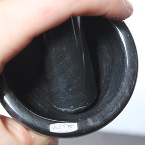 May include: A black mortar and pestle set. The mortar is a deep bowl shape, and the pestle is a cylindrical shape. The set is made of a dark, possibly stone material. The text "MADE IN TAIWAN" is visible on the mortar.