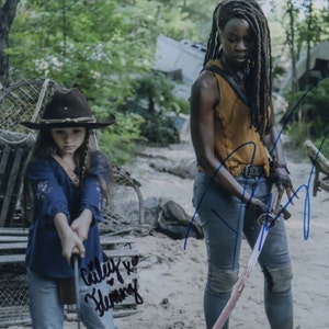 May include: A young girl wearing a brown cowboy hat and a blue shirt holds a black stick. A woman with long dreadlocks and a yellow tank top holds a sword. The image is signed "Giley x  Heming".