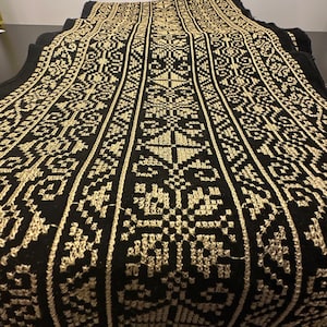 Könnte beinhalten: Schwarzer Stoff mit einem goldenen geometrischen Muster, das in den Stoff eingewebt ist. Das Muster ist ein sich wiederholendes Design aus Quadraten und Rauten.