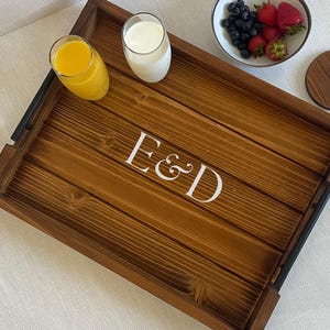 May include: A wooden serving tray with black metal handles. The tray has a natural wood finish and is personalized with the initials "E&D".