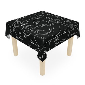 Könnte beinhalten: Schwarze Tischdecke mit einem weißen Muster aus mathematischen Gleichungen. Die Tischdecke ist über einen kleinen Holztisch mit vier Beinen gelegt.