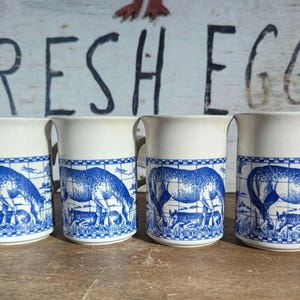 Puede incluir: Cuatro tazas de cerámica blanca con diseños azules y blancos de caballos y un patrón de azulejos azules y blancos. Las tazas tienen un asa en el lado derecho.