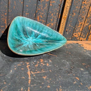 Peut inclure: Un plat en céramique turquoise et marron de forme organique inhabituelle. L'intérieur présente un motif tourbillonnant de turquoise et de marron, avec une finition brillante. Le plat a un bord marron et est probablement vintage.