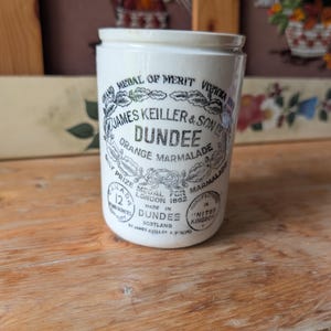 Peut inclure: Un pot en céramique blanche avec du texte imprimé en noir indiquant James Keiller & Son Dundee Orange Marmalade, Grand Medal of Merit Vienna 1873, et Prize Medal for Marmalade London 1862, avec une capacité marquée de 12 fluid ounces.